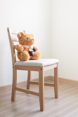 The teddy bear is sitting on a chair in an empty room. family and friendship concept. 