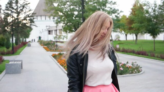 Blond lady spinning in the park with her hair fling oround
