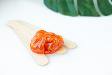Sugar paste or wax honey for hair removal with wooden wax spatulas on a white background. Skin care spa concept.