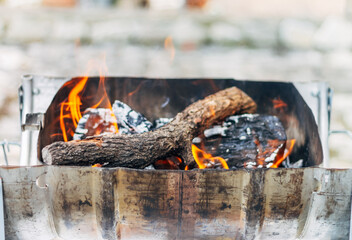 A Homemade barbecue with burning wood. Concept of making a fire at home.