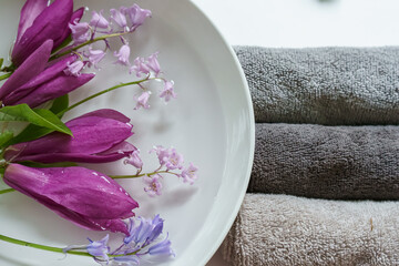 Obraz na płótnie Canvas Arrangement of spring flowers in water and towels for spa, massage shop