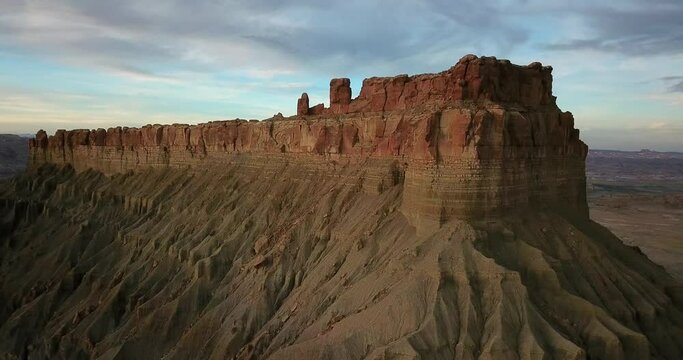 Aerial view moveing away shot, Scenic view of Factory Butte in Utah Badland, Cloudy blue sky in the background