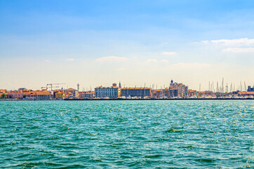Naklejka premium Panoramic view from sea lagoon of Chioggia town cityscape with port and old buildings in historical centre, blue sky background in summer day, Veneto Region, Northern Italy