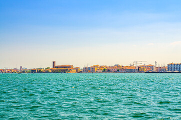 Naklejka premium Panoramic view from sea lagoon of Chioggia town cityscape with Saint Domenico catholic church and old buildings in historical centre, blue sky background in summer day, Veneto Region, Northern Italy