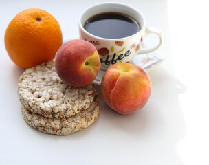 a cup of coffee, crispbreads and fruit on a white background close-up