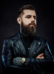 Obraz premium Portrait of a tattooed cool bearded man in a leather jacket with arms crossed