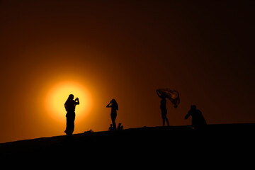 Fototapeta na wymiar group of people walking on the desert of Dubai at sunset