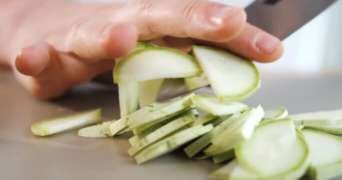 Close up of cutting zucchini with knife. Chef cooking vegetables in restaurant.
