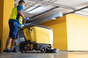 cleaning professional working in garage cleaning with sweeping machine