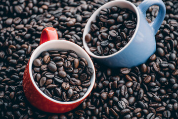 red and blue coffee cups filled and surrounded by coffee beans