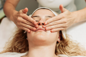 Fototapeta na wymiar Close-up of face massage treatment. Young Caucasian woman. Beauty treatments