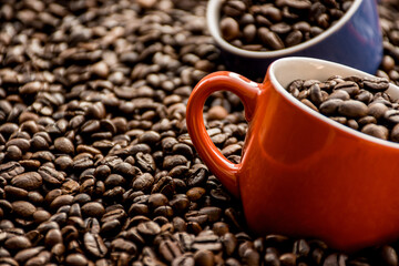 red and blue coffee cups filled and surrounded by coffee beans