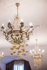 
The vintage chandelier is decorated with beige hanging threads with paper roses to create a romantic atmosphere.
