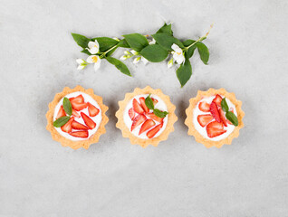 Tartlet with cottage cheese cream and fresh strawberries on a light gray background top view