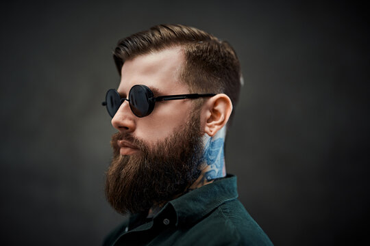 Closeup portrait of a cool bearded male in sunglasses on a dark background