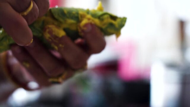 Indian woman tying a arvi arbi leaf marinated in flour and spices with a thin thread before deep frying it to make pakode and bhajiye a popular maharastran dish