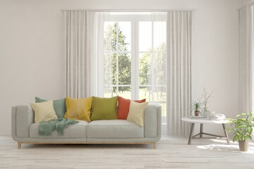 Fototapeta premium White living room with sofa and summer landscape in window. Scandinavian interior design. 3D illustration