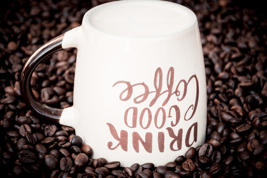 coffee mug with the inscription " Drink good coffee" surrounded by coffee beans