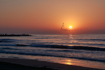 Sunrise on the beach, jetty with fishermen