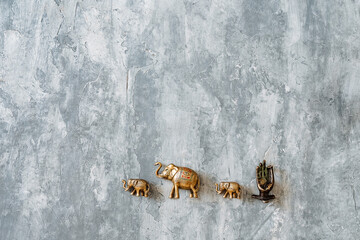 statuettes of copper elephants walking one after another are taken on a gray background, gold figures of Indian elephants, bronze animals in miniature