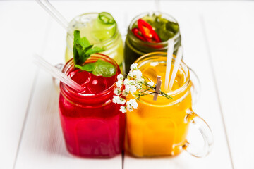 4 different refreshing summer lemonades in jars, red, orange, yellow and green
