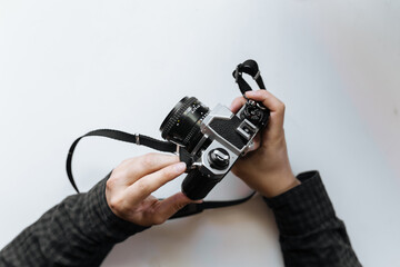 Male man hands holds film in pentax retro camera on a white table. Horizontal