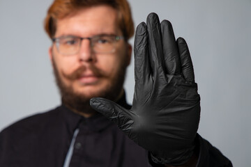 medical health care male person portrait in black glove show stop sign by hand with unfocused face background