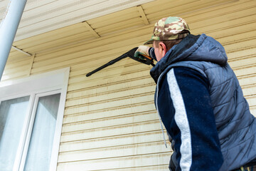Fototapeta premium Cleaning the vinyl siding wall with a high-pressure washer.