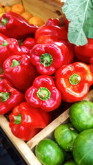 Red bell peppers, zucchini, lettuce leaf with oranges in the background