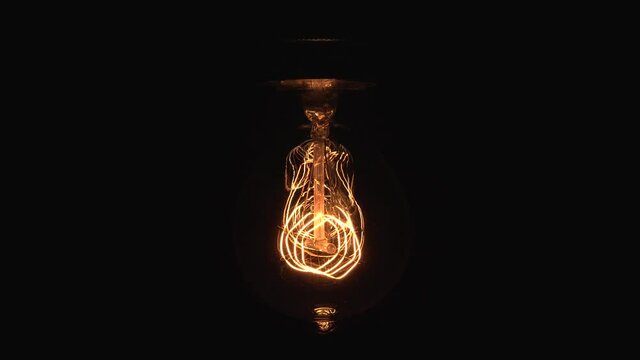 Tungsten light bulb lamp cozy dimming over black background, macro close up shot of old retro vintage light bulb turn off light. Comfort cozy concept. 4k.