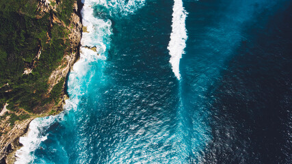 Aerial drone photo top view of the Indian Ocean waves meet or occur with a large rock cliff. Incredibly rich beautiful color water as a background for travel blog or web site. Amazing nature landscape