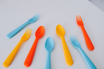 vibrant multicolored forks, kives and spoons (white background)