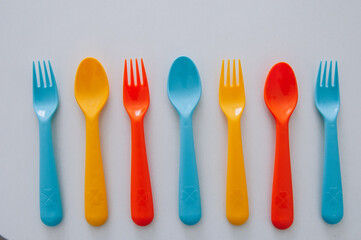 vibrant multicolored forks, kives and spoons (white background)