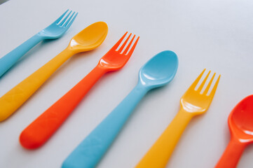 vibrant multicolored forks, kives and spoons (white background)