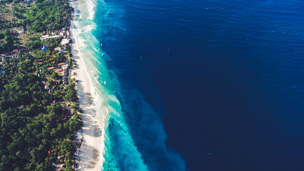 Top view aerial drone photo of stunning colored sea beach with crystalline water fringed with swaying tropical palms and leafy trees. Incredibly beautiful blue ocean meet with powder-white seashore