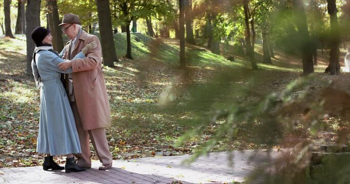 Elderly married couple in love dancing elegant slow dance and having joy in park