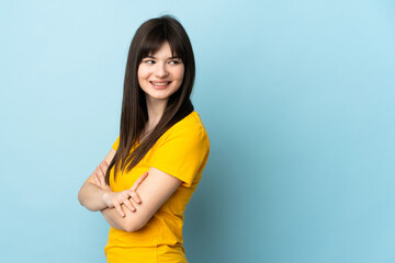 Teenager Ukrainian girl isolated on blue background with arms crossed and happy