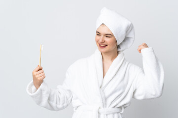 Young woman in a bathrobe holding toothbrush celebrating a victory