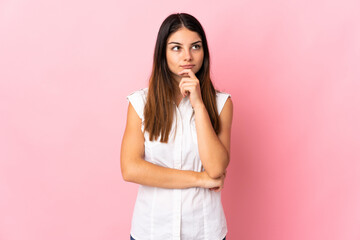 Young caucasian woman isolated on pink background thinking an idea while looking up