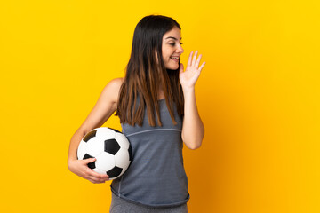 Young football player woman isolated on yellow background shouting with mouth wide open to the side