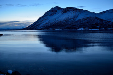 blue frozen fjord and snowy mountain during the blue hour in northern norway