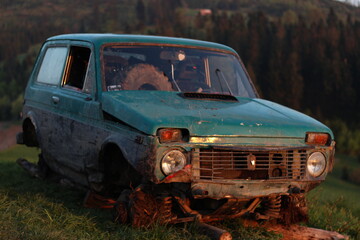 Fototapeta premium Vintage devastated car abandoned on a mountain peak by sunset