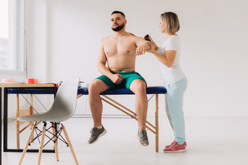 Obraz premium Physiotherapist Applying Kinesio Tape To Patients Injured Shoulder