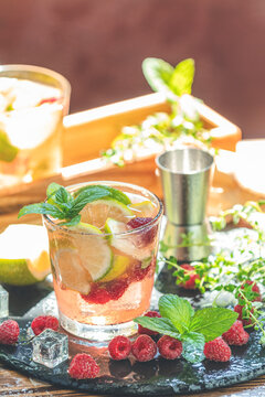 Refreshing mint cocktail mojito with rum, lime, mint, thyme, ice and raspberry. Alcohol or non alcohol summer fresh drink.