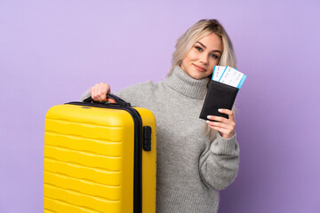 Teenager girl over isolated purple background in vacation with suitcase and passport