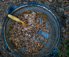 camp pot with buckwheat porridge and a wooden spoon top view