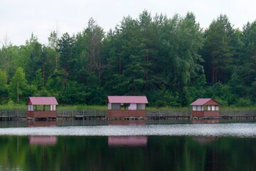 Fototapeta na wymiar fishman houses on a forest lake with reflection on shimmering water