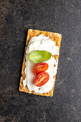 Dieting knackebrot. Crispbread with creamy cheese., cherry tomato and basil leaf.