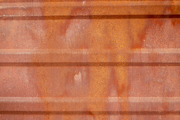 An old fully rusted metal surface with horizontal stripes. Close-up.