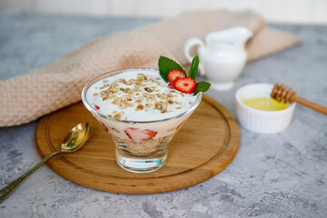 Healthy breakfast of strawberry parfait with fresh fruits, yogurt and granola on a gray table. Oatmeal dessert. Proper, natural nutrition.